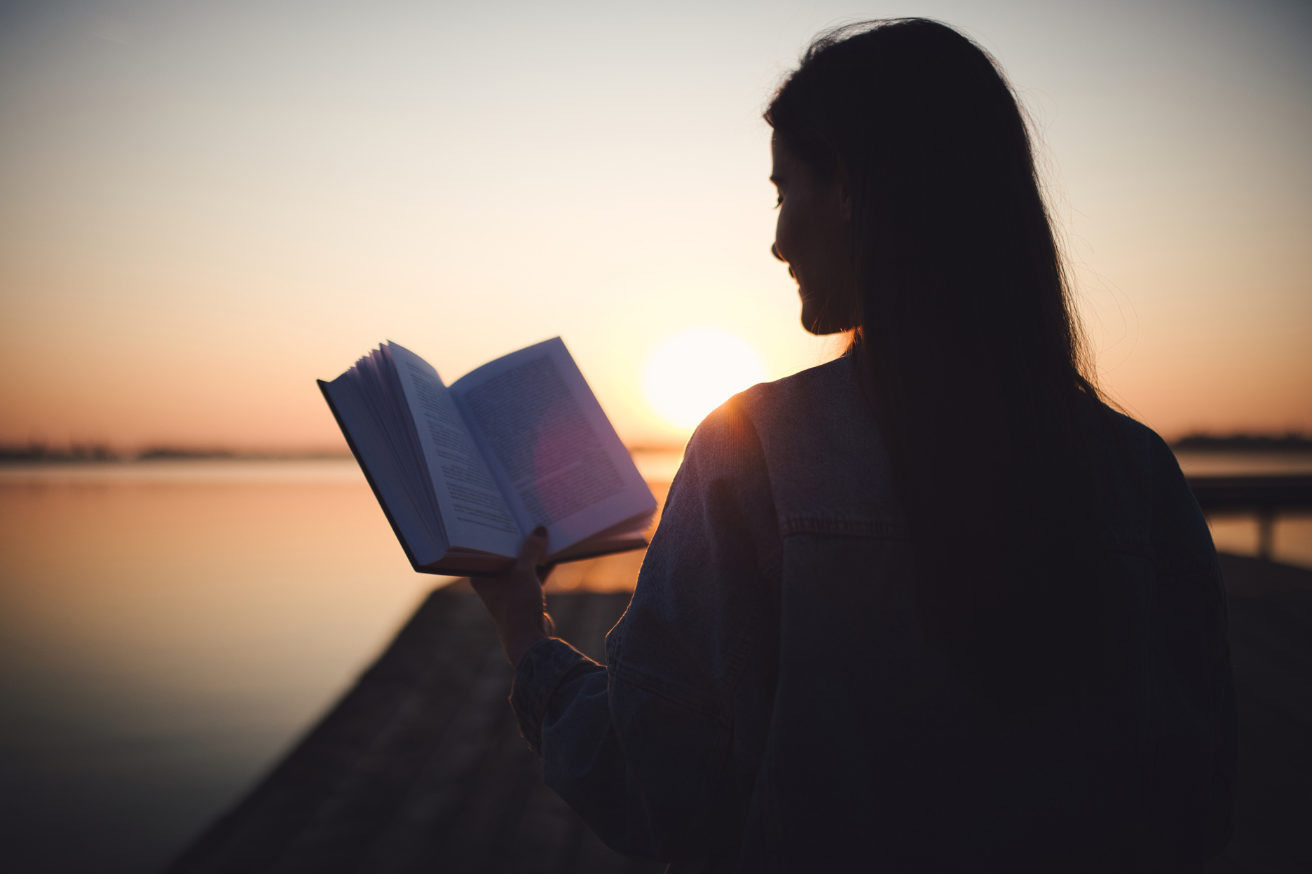 Woman reading book on sunset